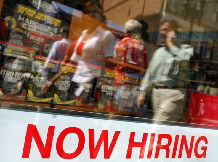 Pedestrians walk past a &quot;Now Hiring&quot; sign in the window of a GNC shop in Boston