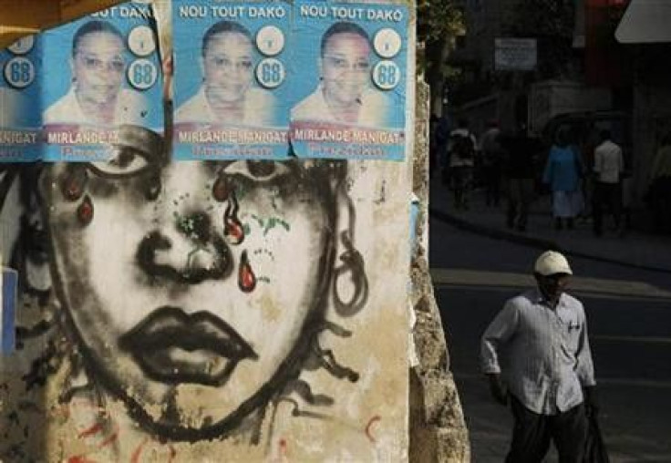 A Haitian man walks next to posters of Haiti's presidential candidate Mirlande Manigat in Port-au-Prince 