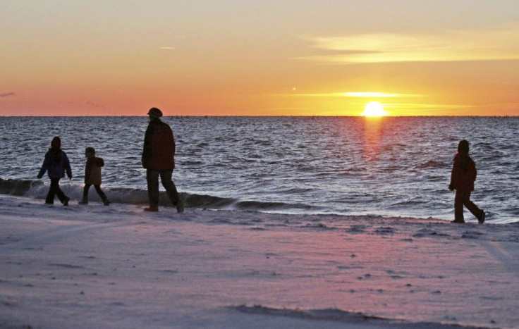 Tourists walk along the snow covered shore of the Baltic Sea island of Fehmarn