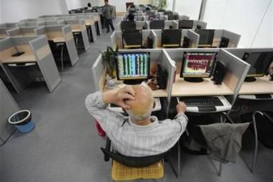 An investor scratches his head in front of a computer screen showing stock information at a brokerage house in Hefei