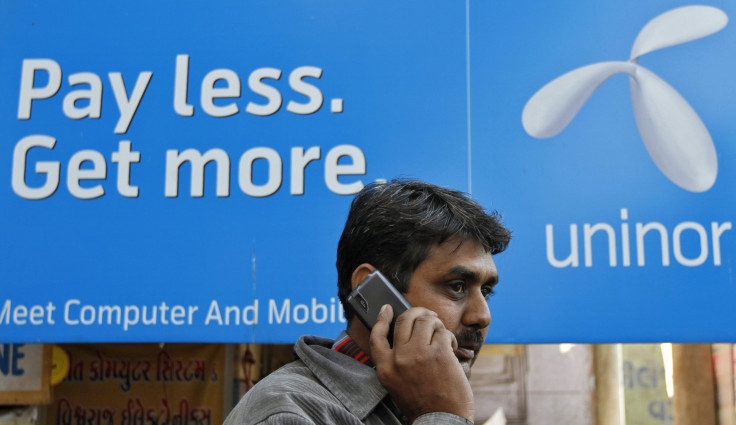 A man speaks on a mobile phone in front of a billboard of Uninor at a market in the western Indian city of Ahmedabad 