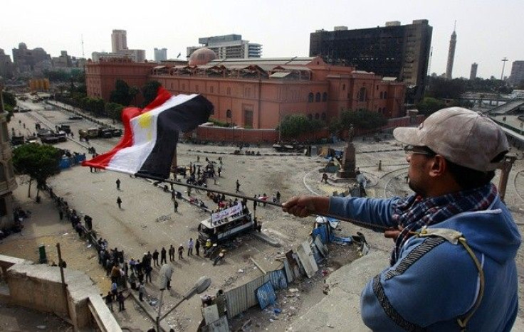 An anti-government protester waves an Egyptian flag at an elevated defense position alongside the Egyptian Museum near Tahrir Square in Cairo February 4, 2011.