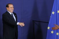 Italy's Prime Silvio Berlusconi reaches to shake hands during a family photo at an European Union leaders summit in Brussels