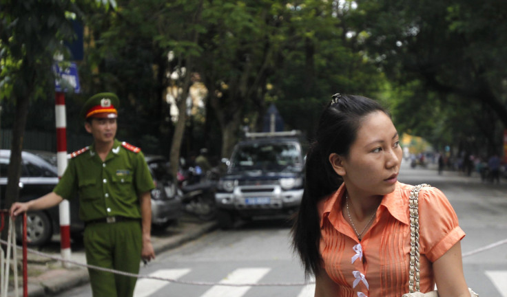 A plainclothes and a uniformed police officer stand in front of a court in Hanoi.