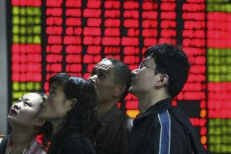 Investors look at an electronic board showing stock information at a brokerage house in Fuyang, Anhui province 