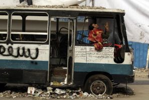 An opposition supporter prays while sitting in a damaged bus near Tahrir Square in Cairo