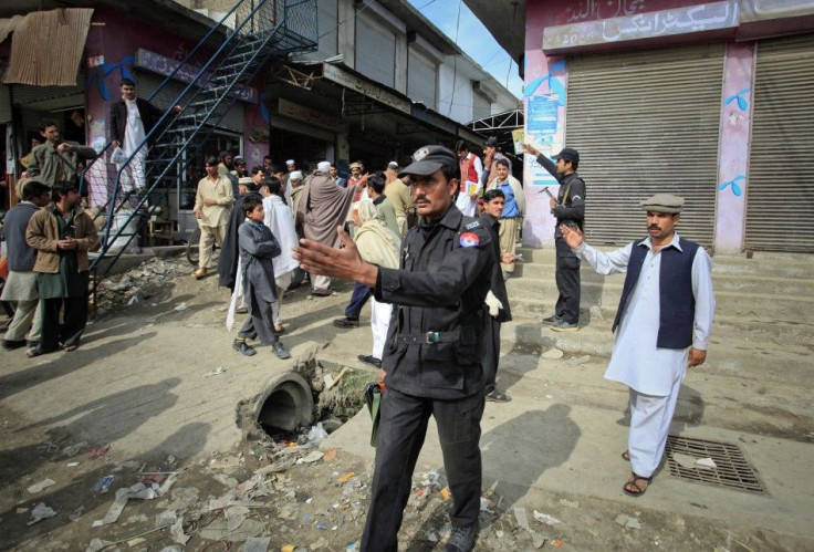 Policemen ask residents to disperse as they stand near the site of a suicide bomb attack at a paramilitary training centre in Mardan, northwest Pakistan February 10, 2011. 