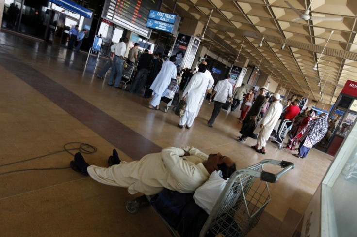 Passenger naps on his luggage while waiting to get on flight, which was cancelled due to strike by employees of Pakistan International Airlines, at Karachi's Jinnah International Airport