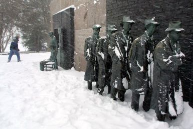 A driving blizzard blows on a Great Depression Bread-Line sculpture as a hiker walks by at the FDR Memorial in Washington
