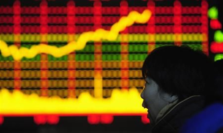 A woman looks at an electronic board with stocks information at a brokerage house in Hefei