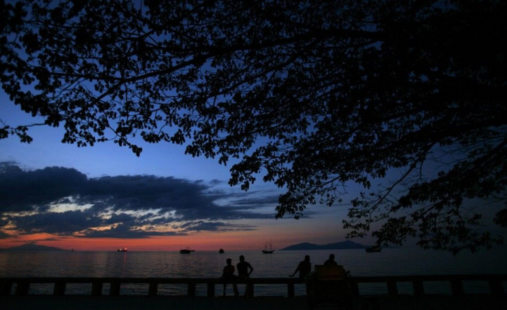 East Timorese sit at a port during sunset in Dili