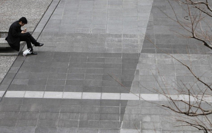 Man sits outside an office building in Tokyo