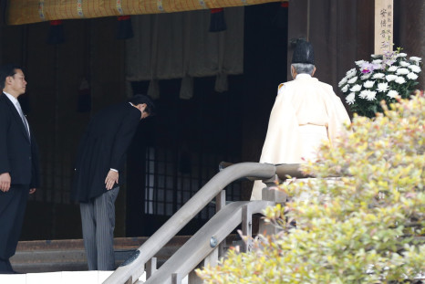 Japan's Prime Minister Shinzo Abe (C) is led by a Shinto priest as he visits Yasukuni shrine