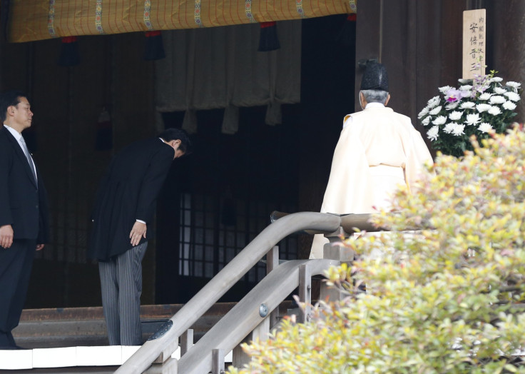 Japan's Prime Minister Shinzo Abe (C) is led by a Shinto priest as he visits Yasukuni shrine