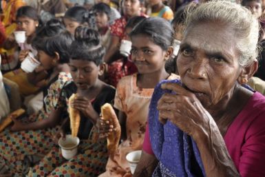 People displaced by flooding eat bread and drink tea in a temporary camp in Batticaloa district