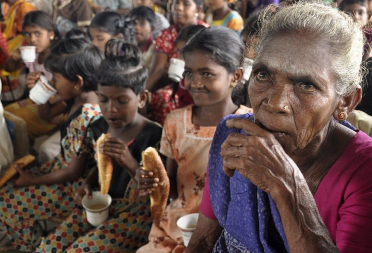 People displaced by flooding eat bread and drink tea in a temporary camp in Batticaloa district