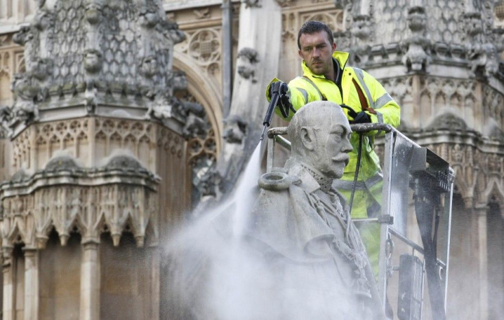 A worker uses a power washer to clean a statue of Britain's King George V outside Westminster Abbey in London