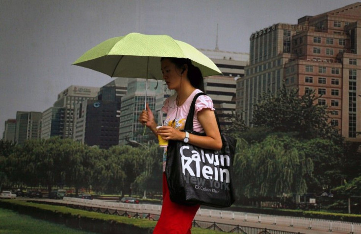 Woman holds an umbrella as she walks past a billboard carrying a bag displaying the name of U.S. fashion label Calvin Klein in central Beijing.