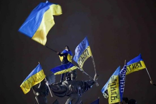  A Pro-European integration protester waves a Ukrainian national flag as she stands on a statue during a mass rally at Independence Square in Kiev