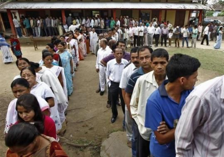  Voters line up to cast their vote outside a polling station in Nakhrai village in Tinsukia district, in Assam.