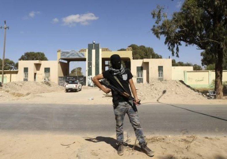  A militia stands guard in front of the entrance to the February 17 militia camp after Libyan irregular forces clashed with them in the eastern city of Benghazi May 16, 2014. 