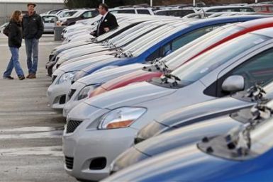 Potential buyers and a salesman look at Toyota Corollas on the lot at Boch Toyota in Norwood