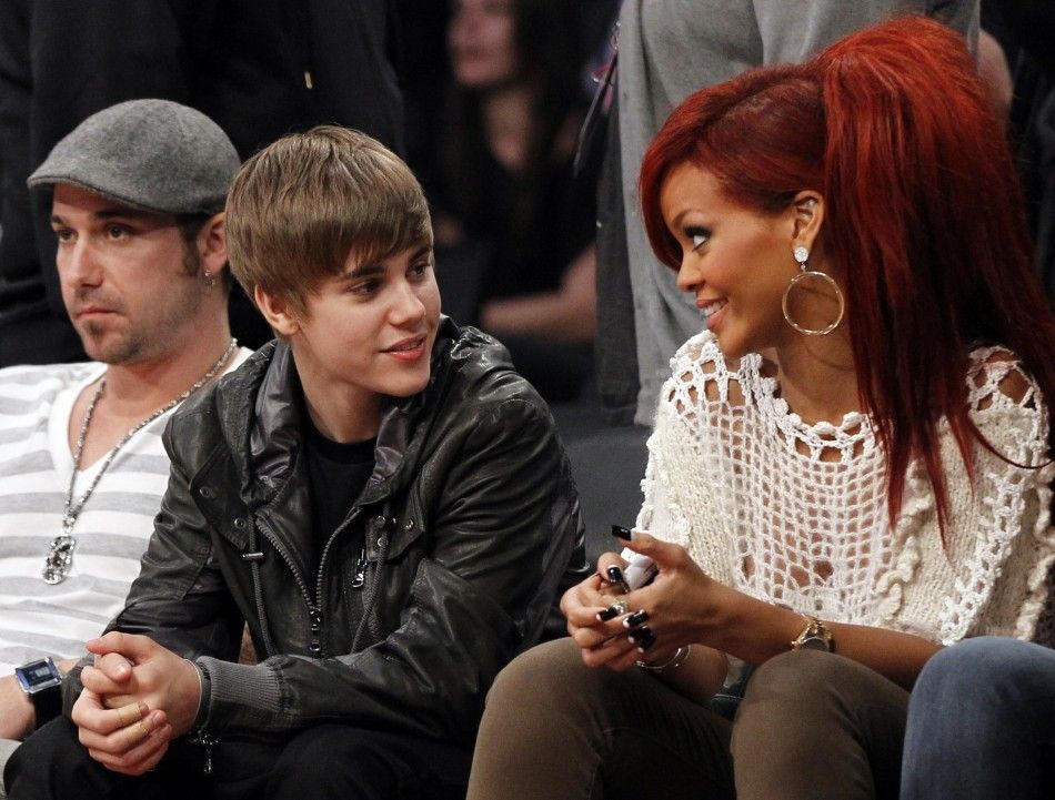 Justin Bieber talks with Rihanna as they sit courtside during the NBA All-Star basketball game in Los Angeles