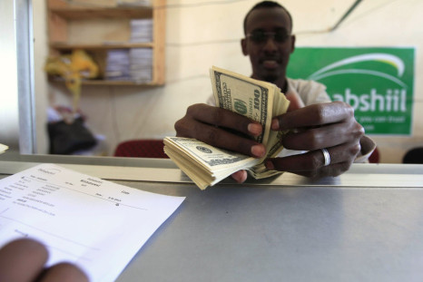 A worker counts U.S. dollars as he serve a customers at a Dahabshiil money transfer office in "Kilometer Five" street of Soobe village, southern Mogadishu