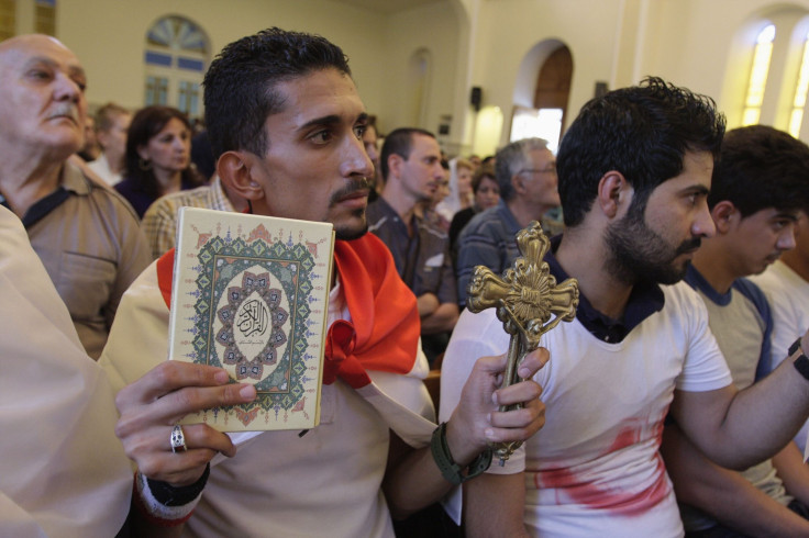 An Iraqi man carrying a cross and a Koran attends a mass at Mar Girgis Church in Baghdad, July 20, 2014. 