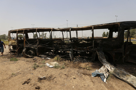 A man walks past a burnt bus in Taji, north of Baghdad July 24, 2014