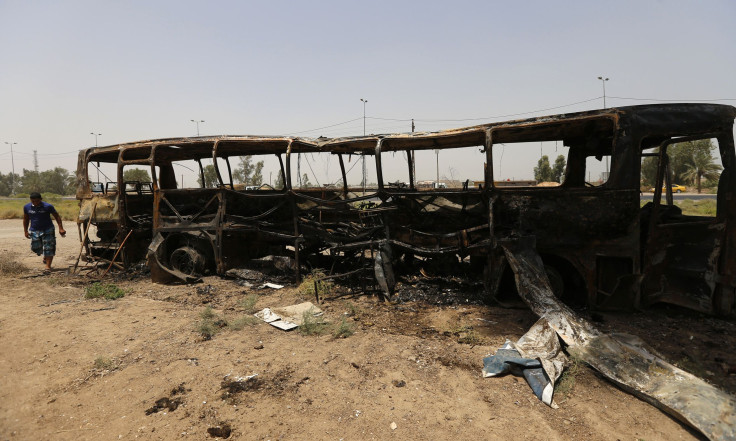 A man walks past a burnt bus in Taji, north of Baghdad July 24, 2014