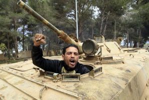 A man gestures as he sits in an army armoured vehicle in Shahat