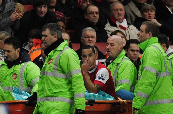 Arsenal's Theo Walcott watches his team play as he is carried off the pitch in a stretcher during their English Premier League soccer match against Stoke City at the Emirates Stadium in London.