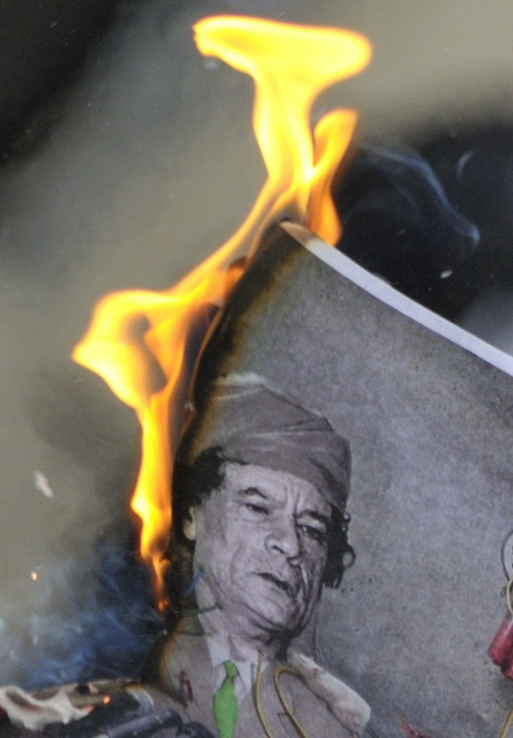 A man burns a picture of Libyan leader Muammar Gaddafi during a demonstration near the Libyan consulate in Paris