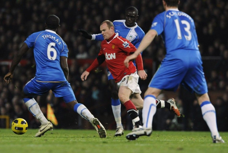 Manchester United's Rooney runs past Wigan Athletic's defenders during their English Premier League soccer match in Manchester.