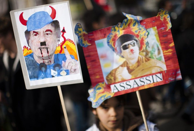 A young boy holds satirical posters of Libya's leader Gaddafi during a demonstration in solidarity with the anti-government protests in Libya, in Geneva 
