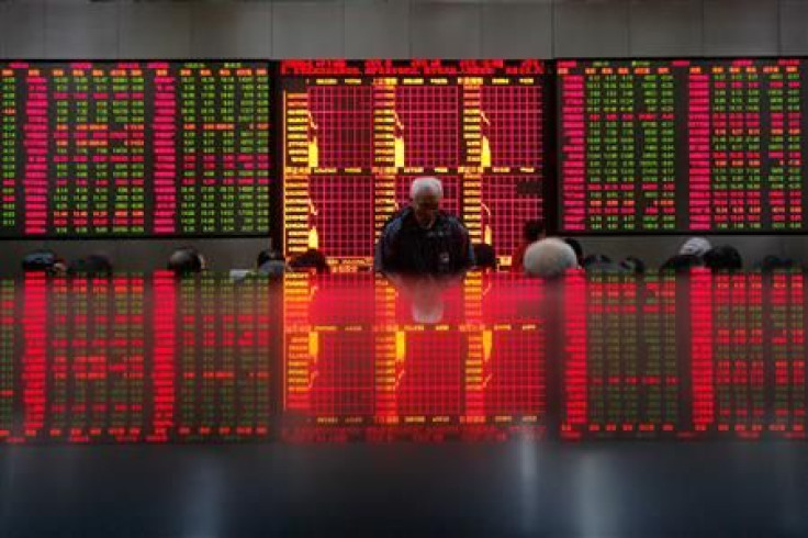 People look at an electronic board at a brokerage house in Shanghai