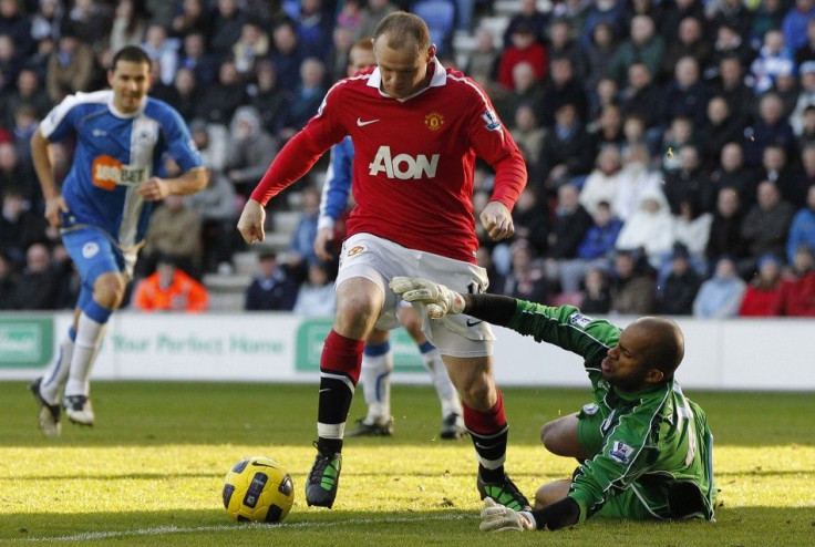 Wigan Athletic's al Habsi challenges Manchester United's Rooney during their English Premier League soccer match at the DW Stadium in Wigan.