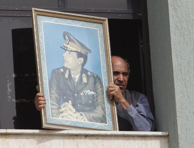 A man holds a picture of Libya's leader Muammar Gaddafi from the window of a bank in Sabratha
