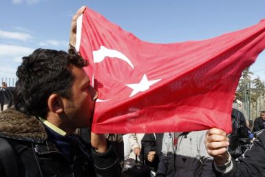 A Turkish worker kisses the Turkish flag at the Libyan and Tunisian border crossing of Ras Jdir after fleeing unrest in Libya