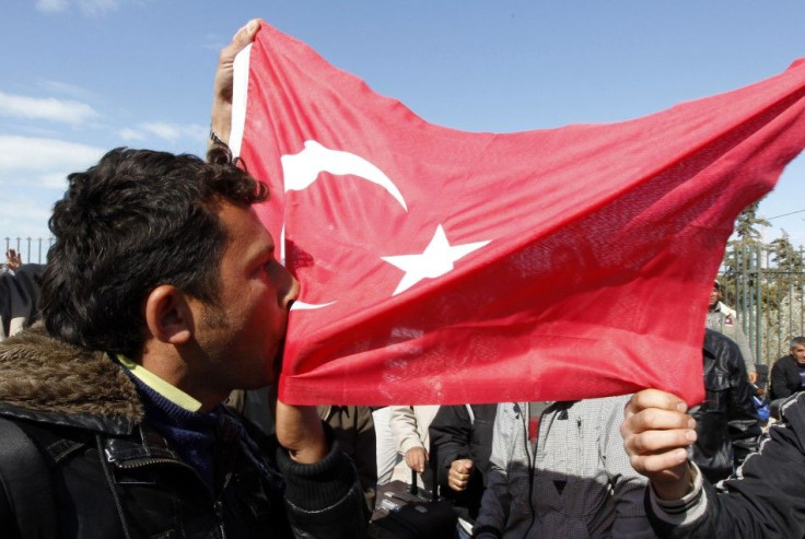 A Turkish worker kisses the Turkish flag at the Libyan and Tunisian border crossing of Ras Jdir after fleeing unrest in Libya