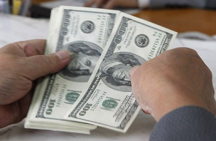 A customer counts U.S. dollar notes