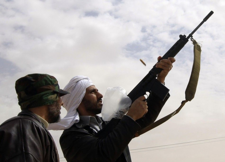 A rebel celebrates news of rebels taking control of Brega by firing his gun in the air on outskirts of Ajdabiya, on the road leading to Brega