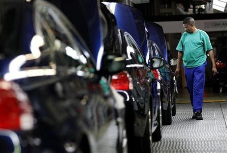 A worker walks near a row of cars at BMW's manufacturing plant in Rosslyn, outside Pretoria