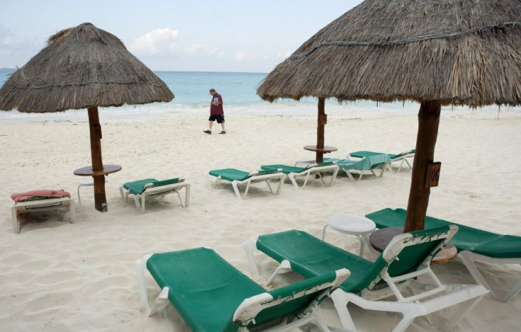 Tourist walks past empty beach chairs in Cancun 
