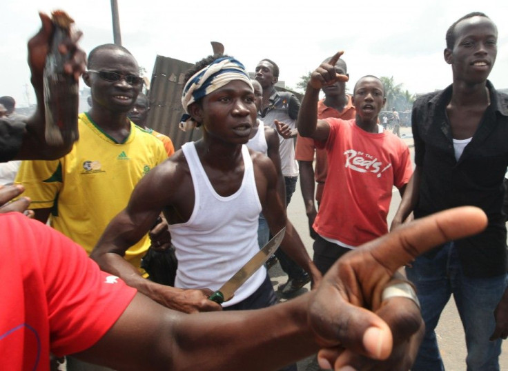 Anti-Gbagbo protester stands with knife near a roadblock and burning tyres in the Abobo area of Abidjan