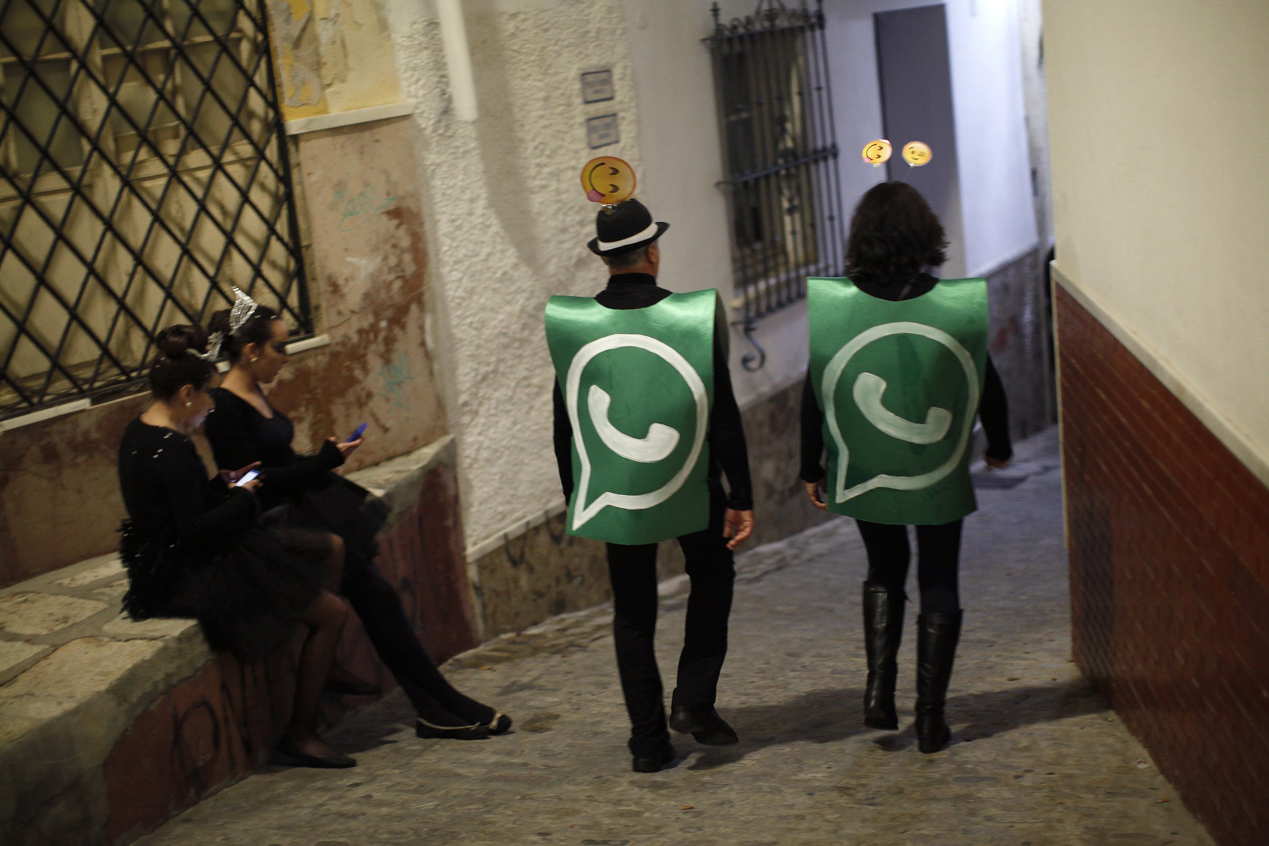  WhatsApp status settings are shown on the backs of two people wearing green WhatsApp logo costumes.