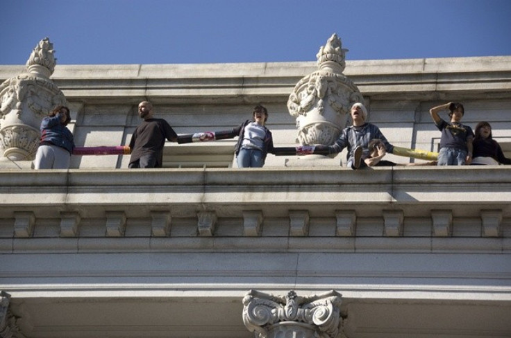 Protesters linked together call out to the crowd from a ledge on the south side of Wheeler Hall.