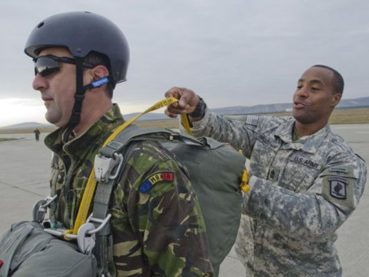 A U.S. soldier assists his Romanian counterpart