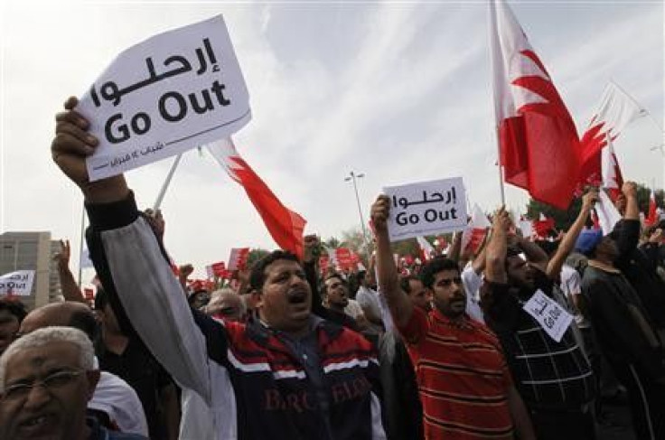 Anti-government protesters hold placards in front of Bahrain's prime minister's palace